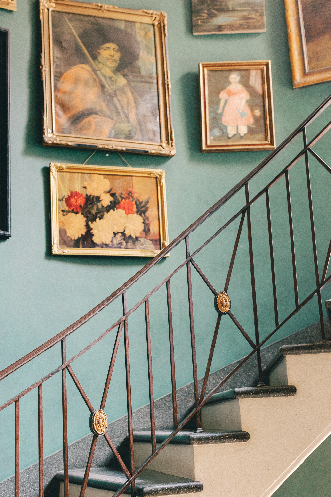 grand staircase with European oil paintings on sage green walls inside Greencrest Manor Battle Creek Michigan