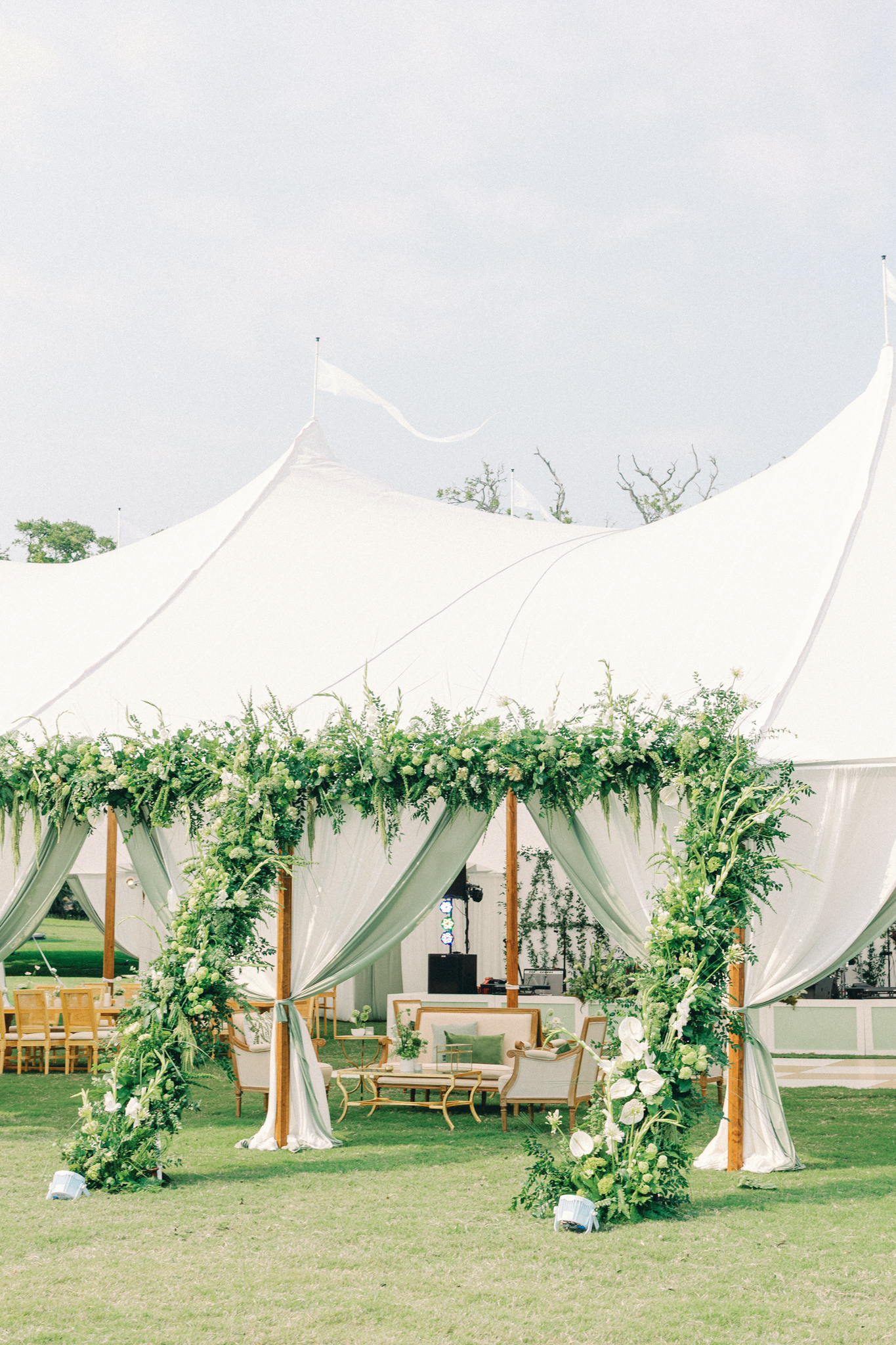 White sailcloth tent with a greenery arch and lounge seating, a rain-ready option for northern Michigan wedding venues