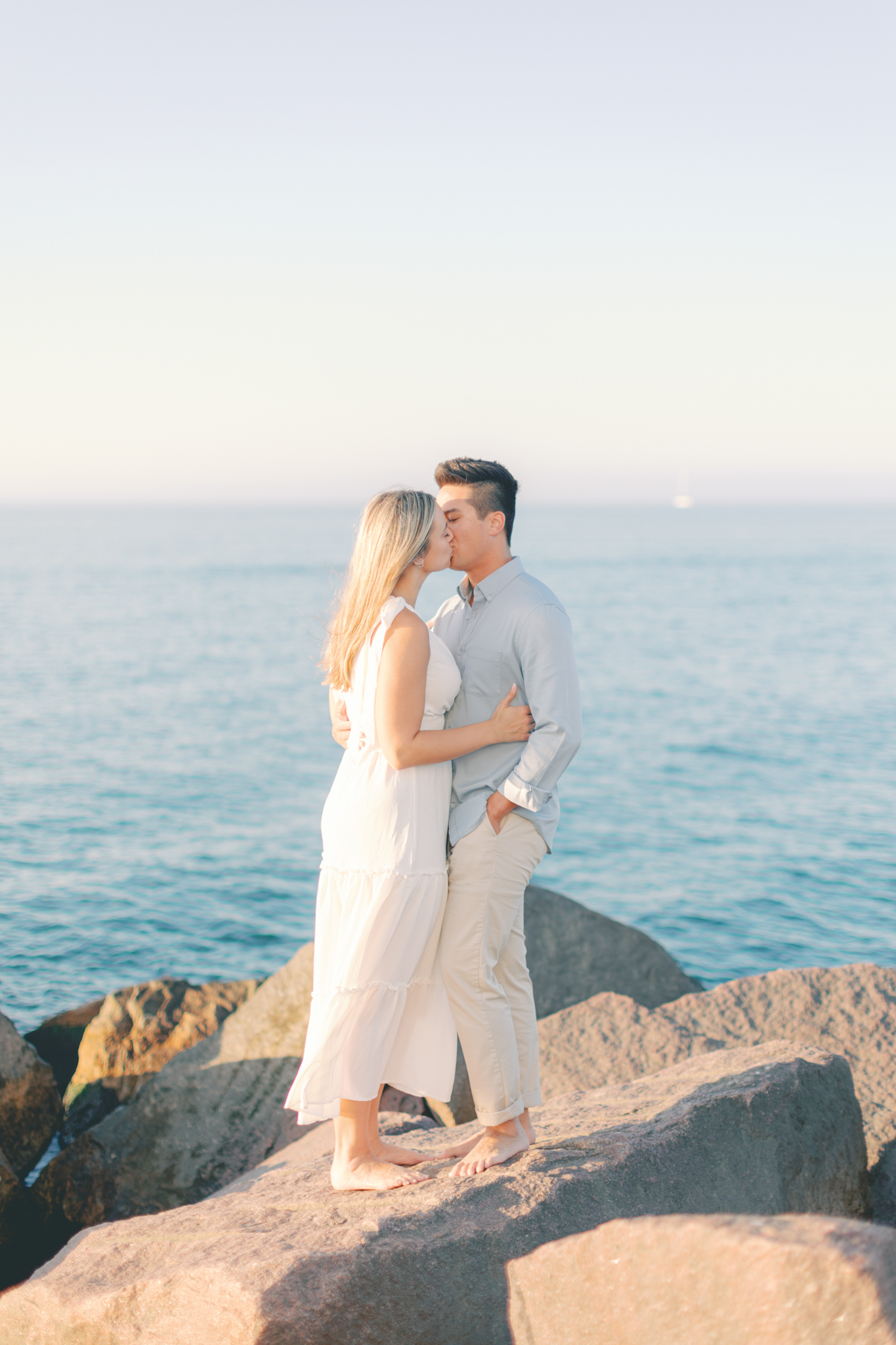 Haley and Andrew share a kiss on the breakwater rocks during their Lake Michigan engagement photos in Michigan City