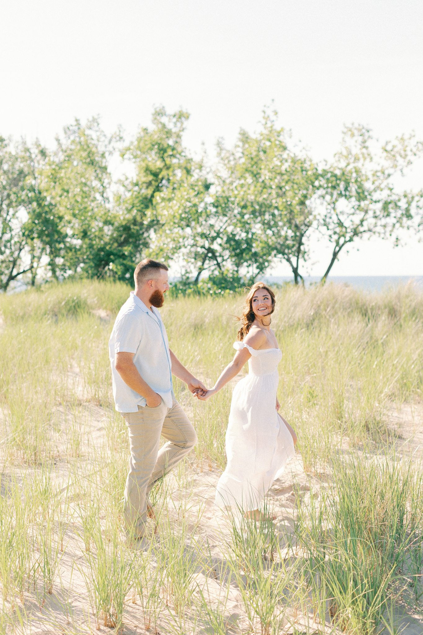 Liz and Kyle walk through the dune grass at Warren Dunes State Park during their Lake Michigan engagement photos