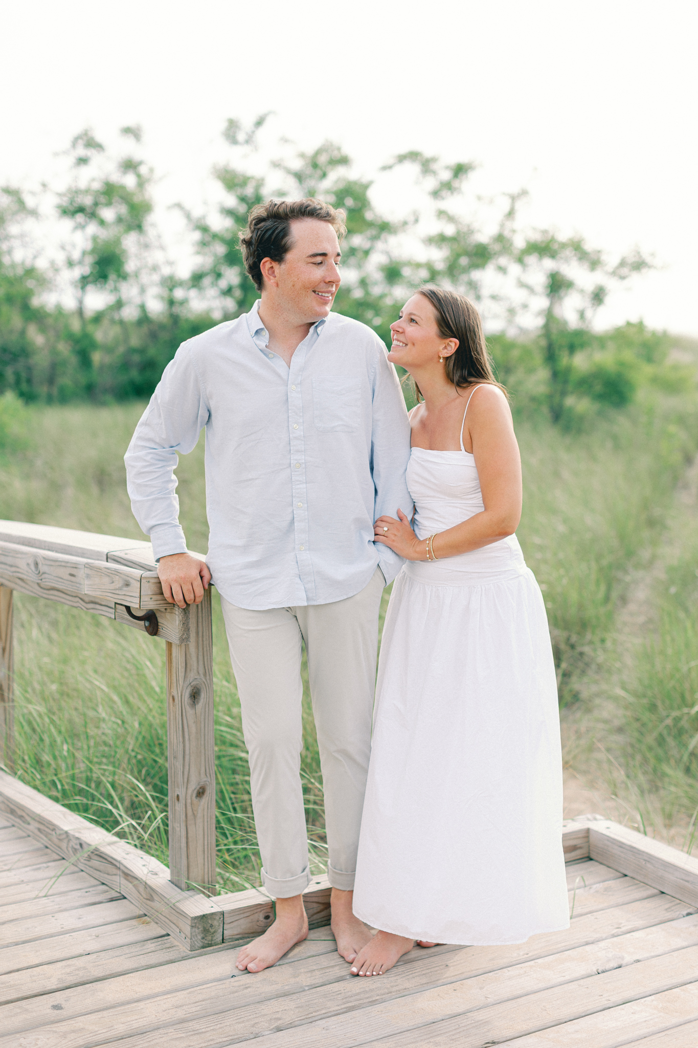 Lauren and Jason on a wooden boardwalk lined with dune grass during their New Buffalo Michigan engagement photos