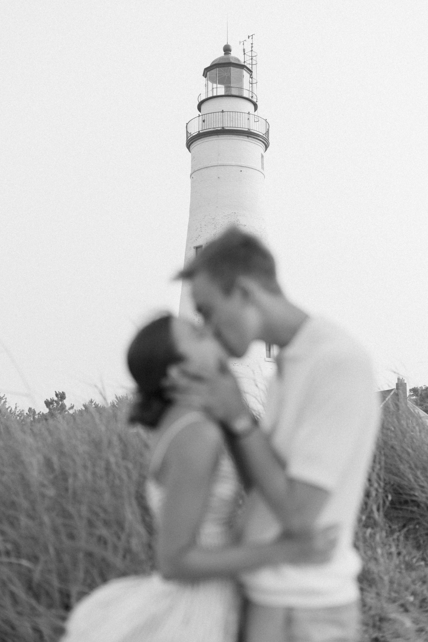 Black and white photo of Emma and Caleb kissing in front of the Fort Gratiot Lighthouse during their Port Huron Michigan engagement photos